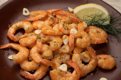 Gamba's in knoflookolie met citroen en dille in een pan