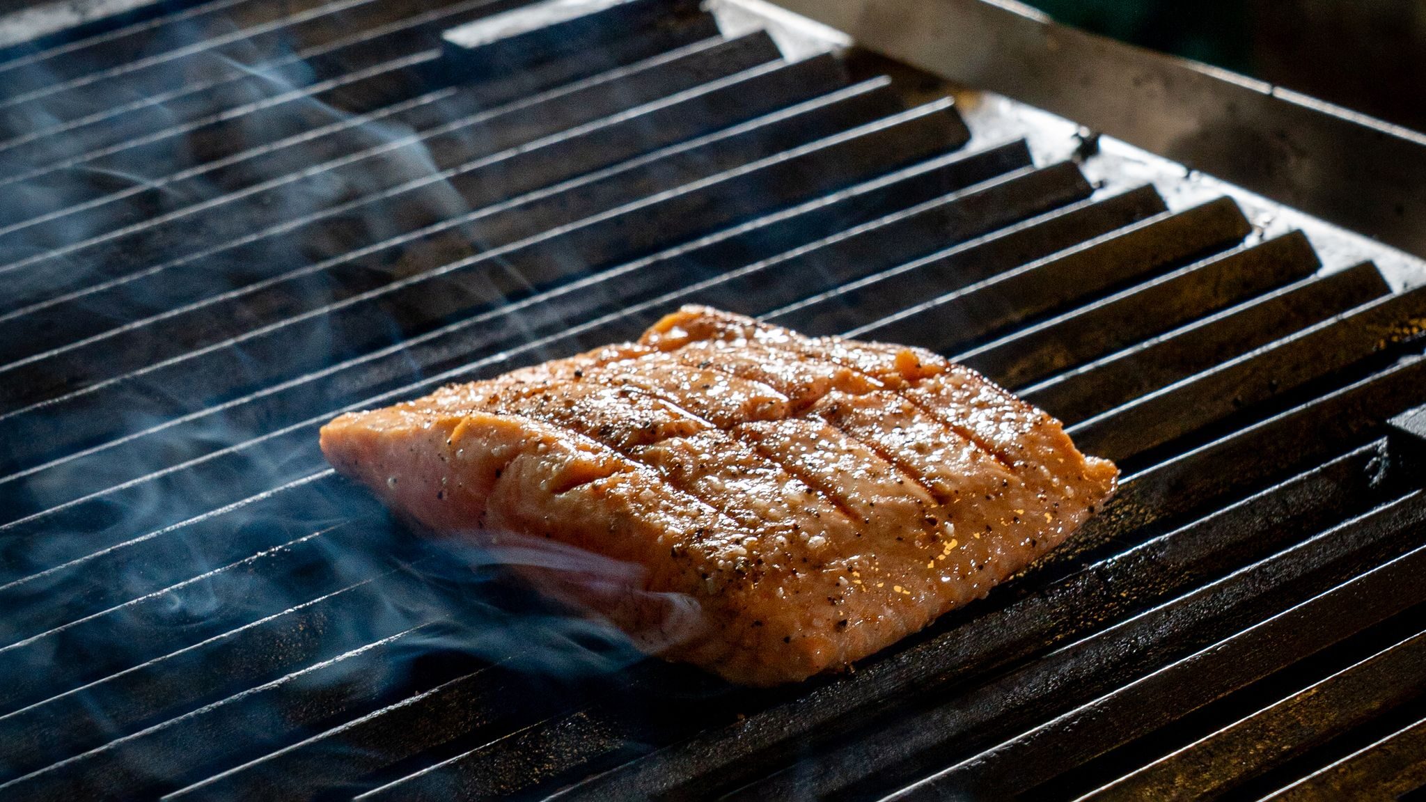 Zalmfilet met grillstrepen gaart op het rooster van een kamado
