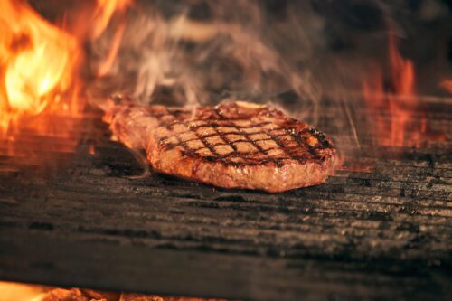 Ribeye wordt boven open vuur dichtgeschroeid met duidelijke grillstrepen
